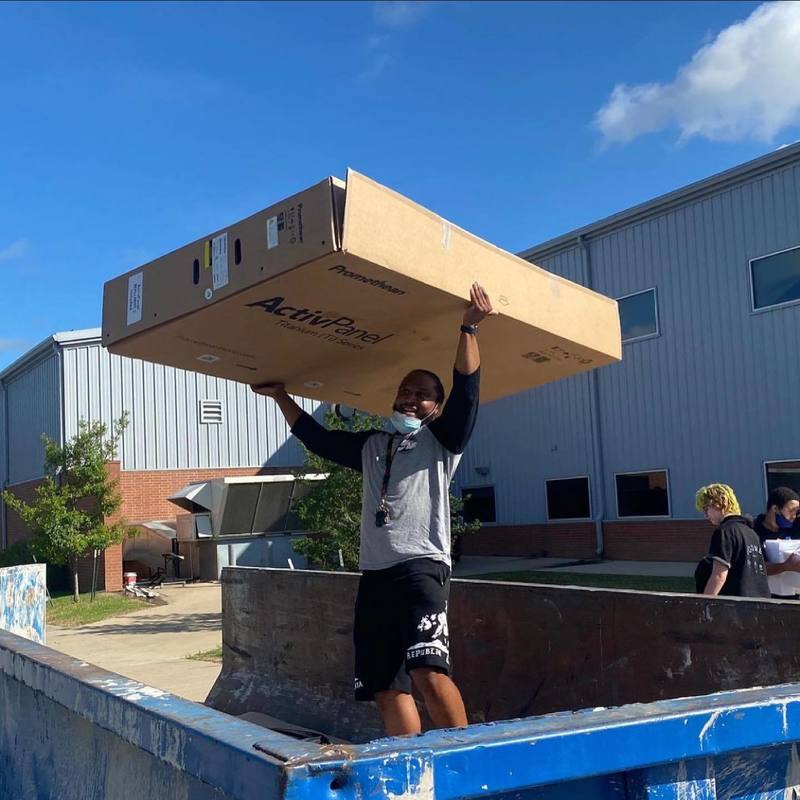 staff lifting large box out of dumpster